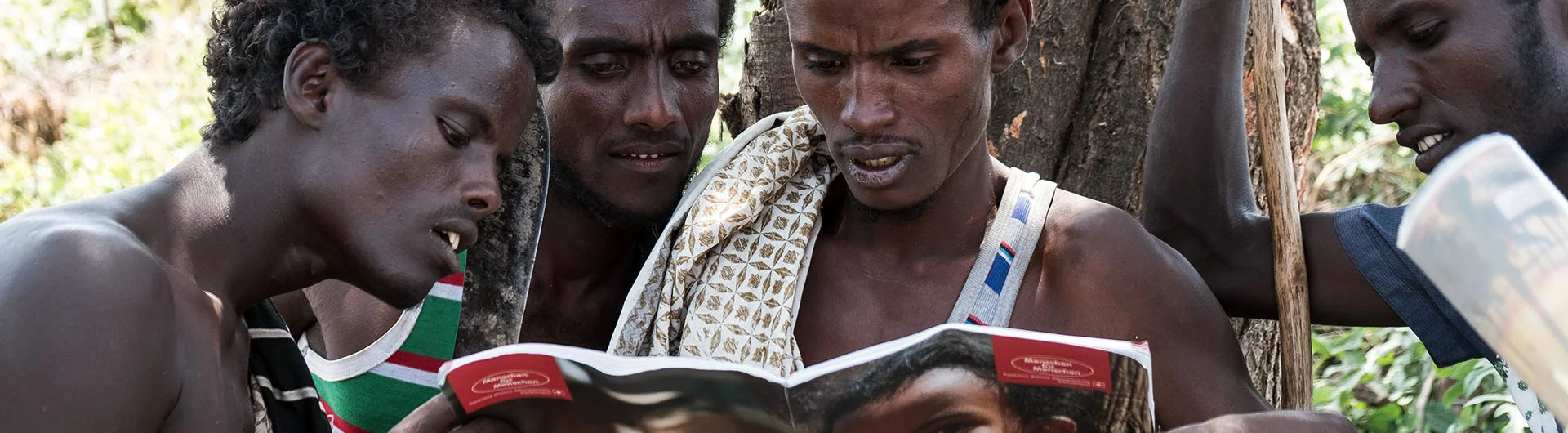 Afar-Nomaden betrachten einen Jahresbericht | Stiftung Menschen für Menschen Afar-Nomaden betrachten einen Jahresbericht der Stiftung Menschen für Menschen