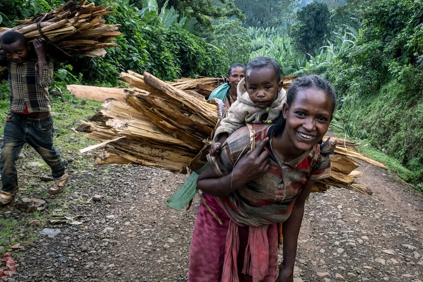 Holzträgerin mit Kind | Stiftung Menschen für Menschen Mutter trägt Kind und Holzbündel auf dem Rücken