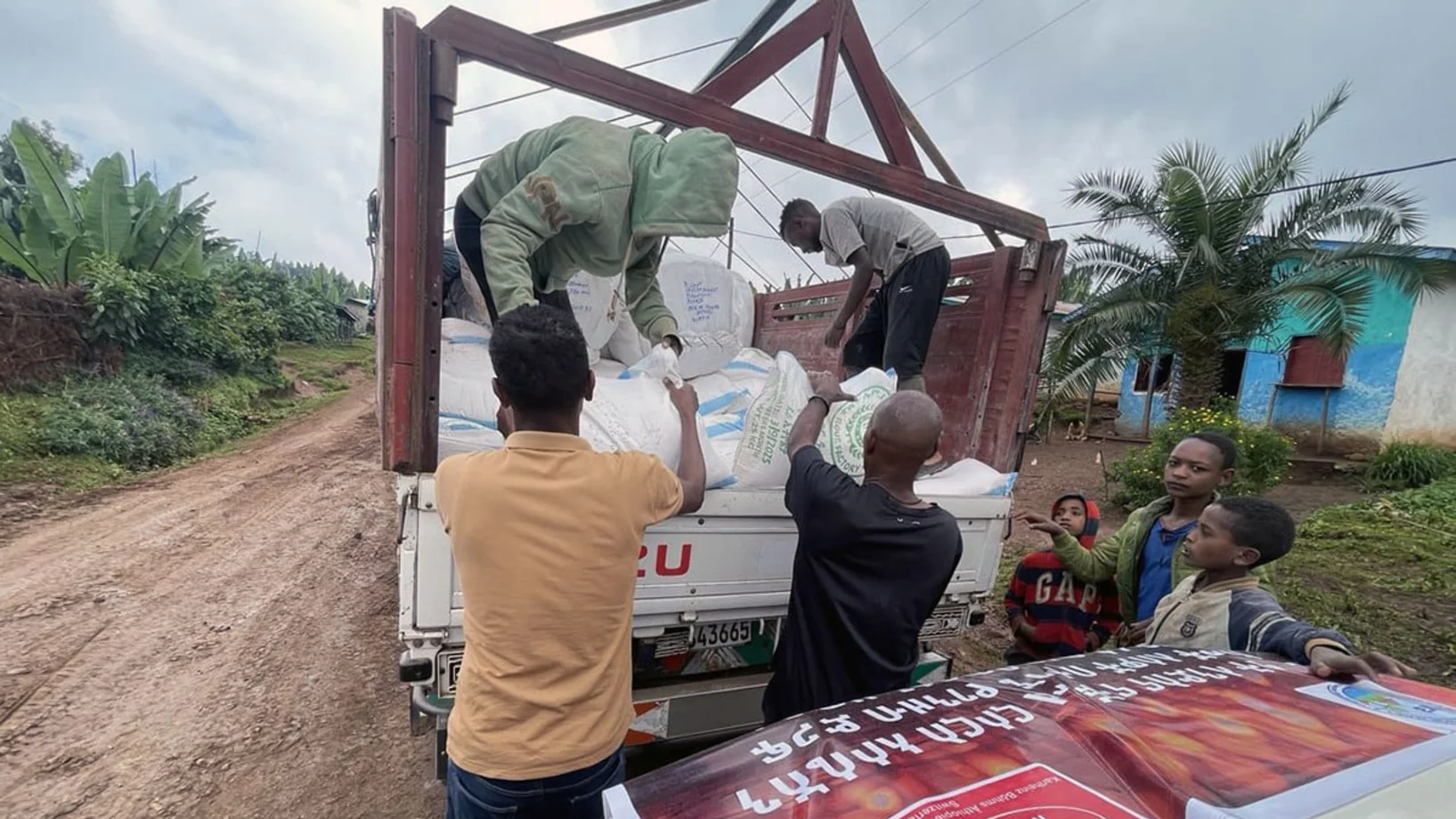 Lastwagen mit Nothilfe-Paketen in Raphe | Stiftung Menschen für Menschen Menschen laden Nothilfe-Pakete vom Lastwagen ab